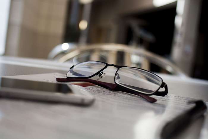 Glasses on a table with a phone and papers