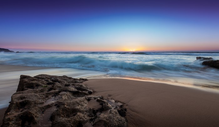 Long exposure of waves crashing on a beach at sunset
