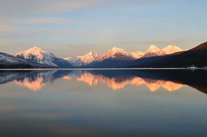 Snow-capped mountains reflected in a calm lake at sunrise