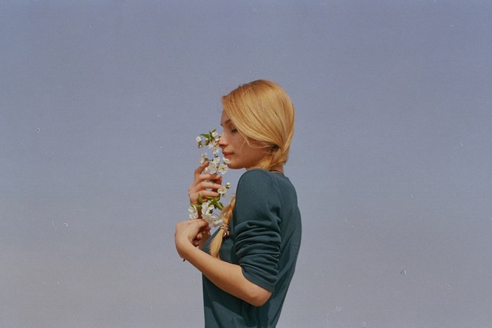 Woman smelling white flowers against a blue sky