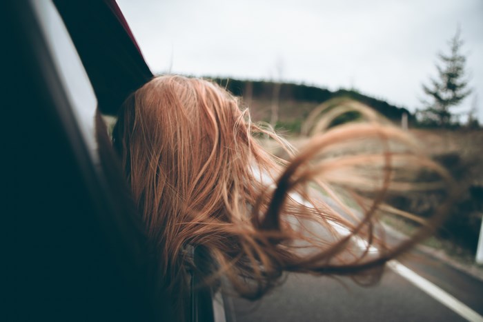 Person with ginger hair in a car with wind blowing