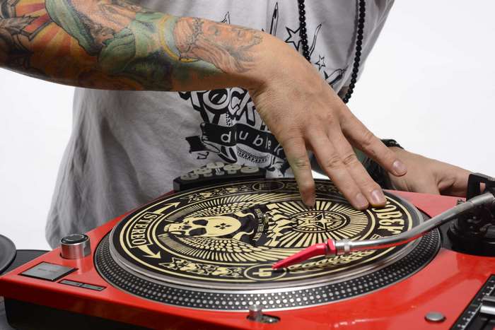 DJ scratching on a turntable with tattoos