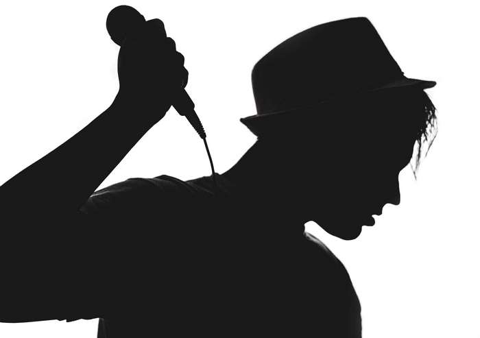 Silhouette of a man in a hat holding a microphone