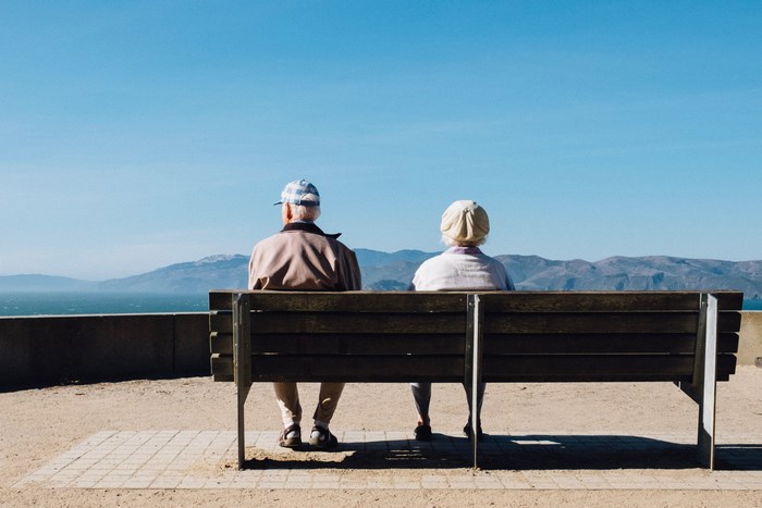 Elderly couple sitting on a bench overlooking the ocean