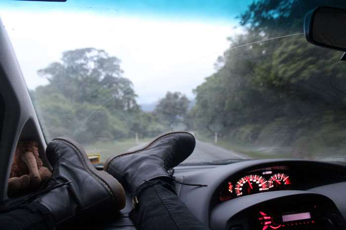 Feet on dashboard during a road trip through a forest