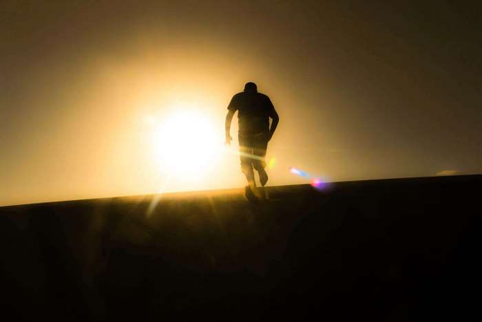 Silhouette of a man walking towards the sun at sunset