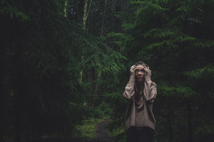 Woman in a sweater in a dark forest
