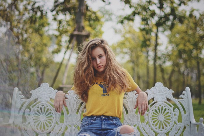 Woman in yellow YMCA shirt on ornate white bench