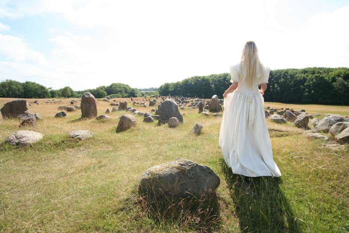Woman in white dress walking through stone field