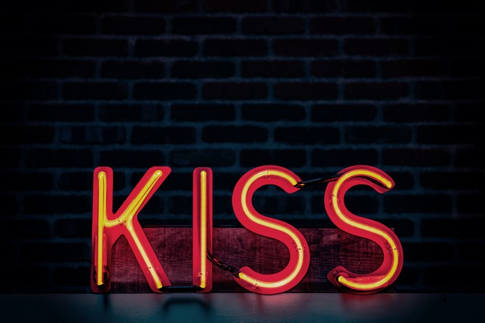Neon sign spelling KISS on a brick wall