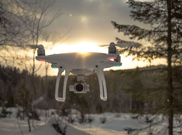 DJI Phantom 4 drone flying in snowy forest at sunset