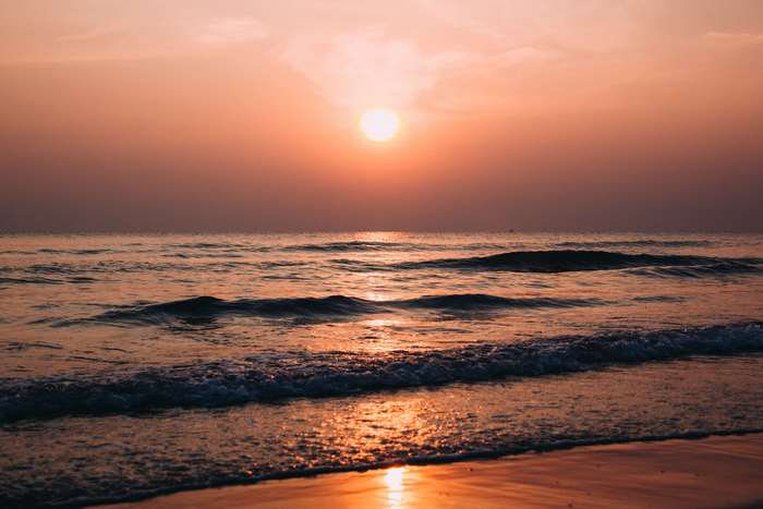 Sunset over the ocean with waves on the beach