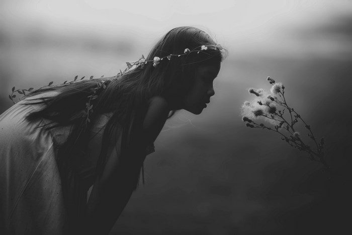 Girl with flower crown smelling a flower