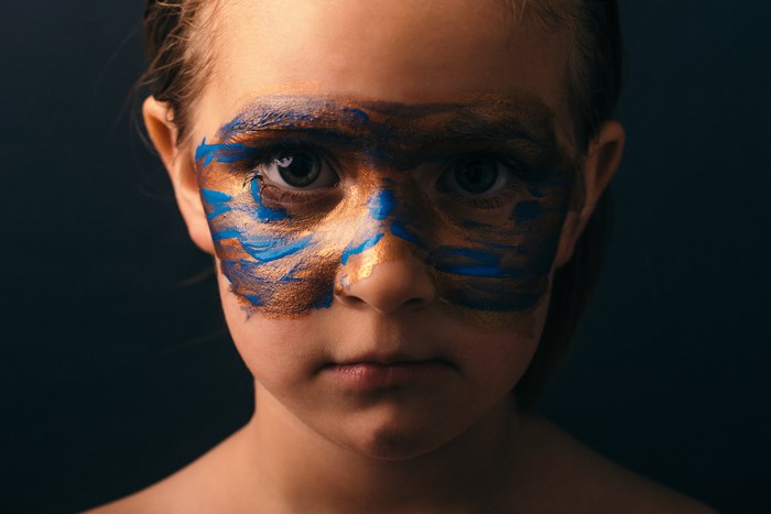 Child with painted face looking at camera