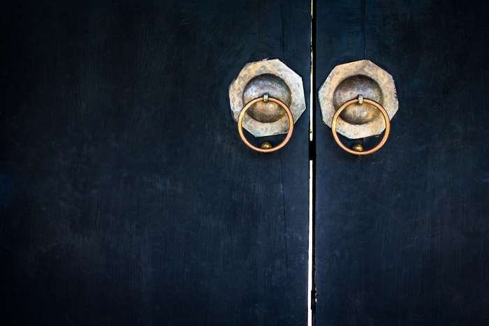 Antique brass door knockers on a dark wooden door