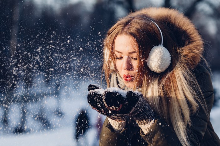 Young woman blowing snow in a winter scene
