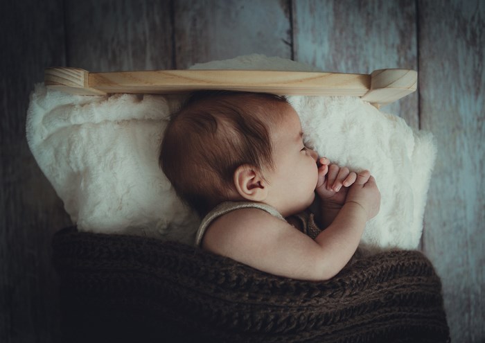 Baby sleeping in a wooden cradle with a blanket