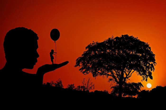 Silhouette of a man holding a child with a balloon