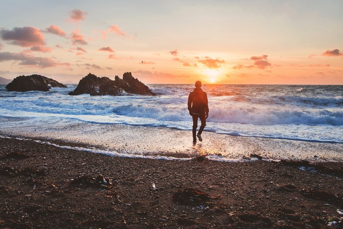 Man walks into the ocean at sunset