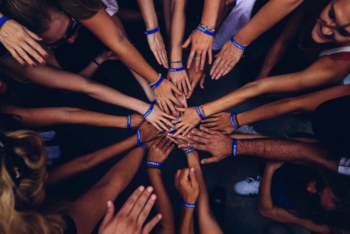 Group of people with hands in the center wearing blue wristbands