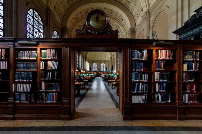 Interior of a grand library with bookshelves and a clock