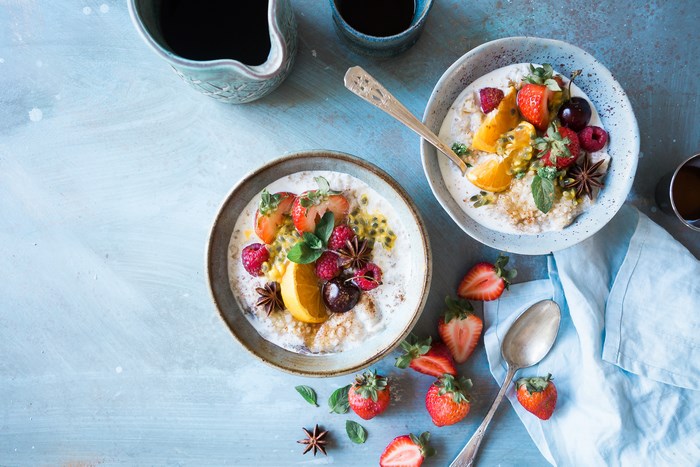 Two bowls of oatmeal with fruits and coffee