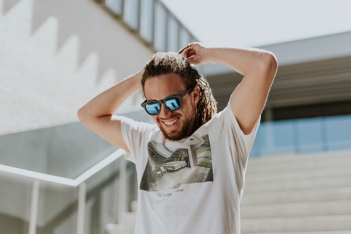Man with dreadlocks and sunglasses smiling