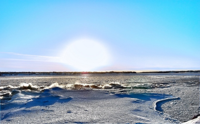 Frozen landscape with sun over water