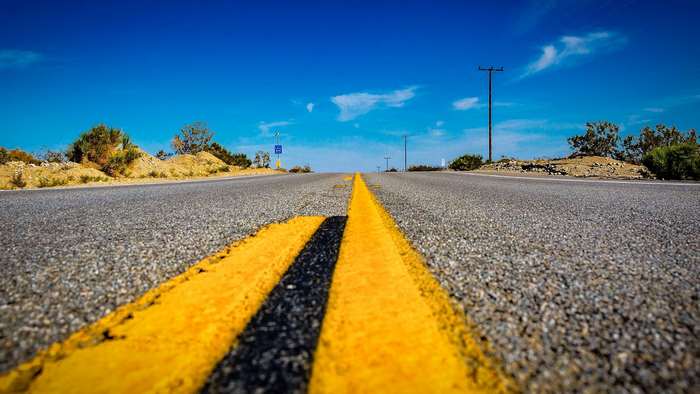 Straight desert highway with yellow lines under blue sky