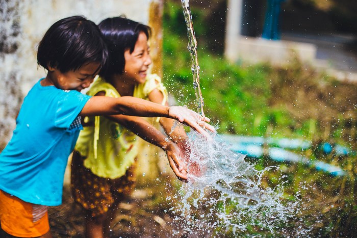 Two children playing in running water