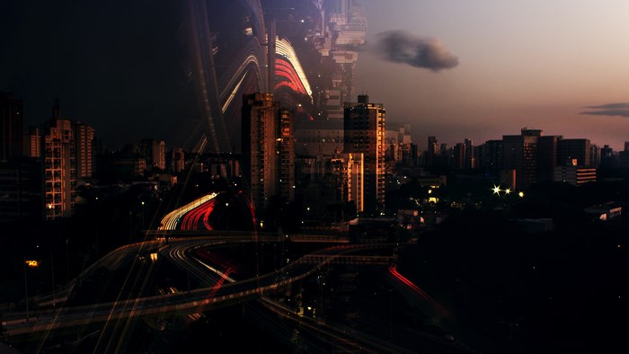 Double exposure of city skyline and freeway at dusk
