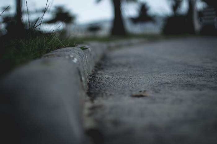 Blurry curb and asphalt with trees in background