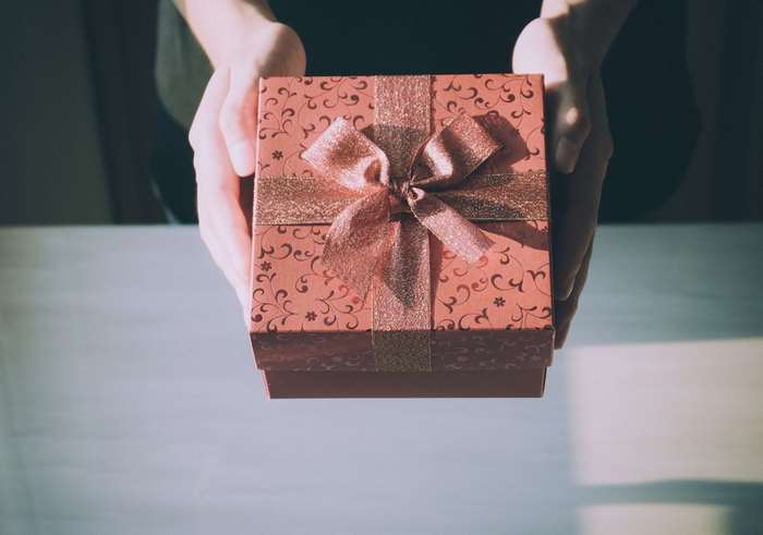 Hands holding a decorated gift box with a ribbon