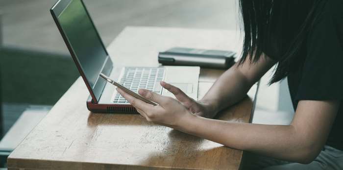 Woman using laptop and smartphone at table