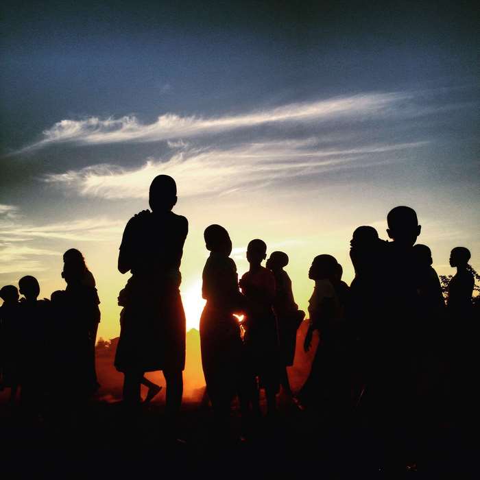Silhouettes of people against a sunset sky