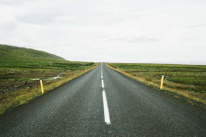 Endless asphalt road through green landscape