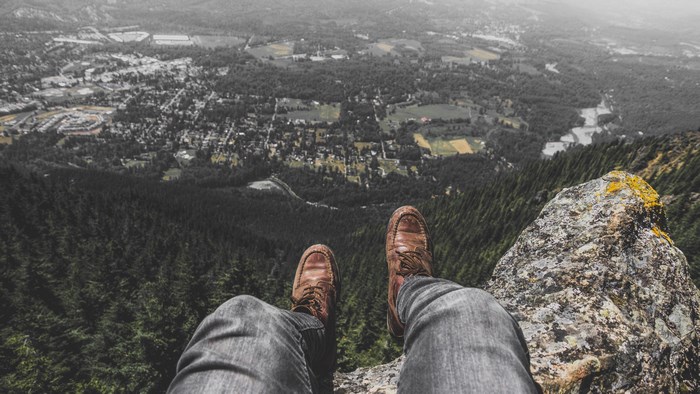 Person sitting on a cliff edge overlooking a town