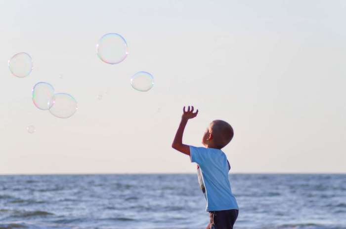 Boy playing with bubbles at the beach