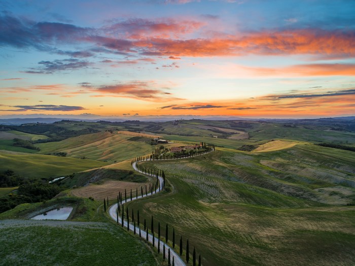 Winding road through rolling hills in Tuscany at sunset