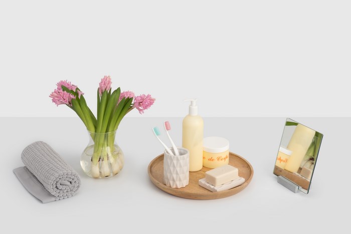 Pink hyacinths, toiletries, and a rolled towel on a surface