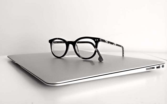 Black eyeglasses on a silver laptop
