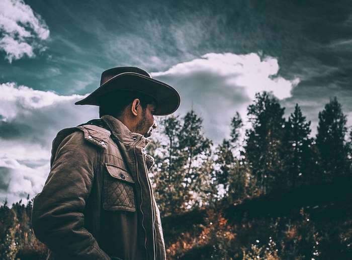 Man in cowboy hat and jacket in a forest