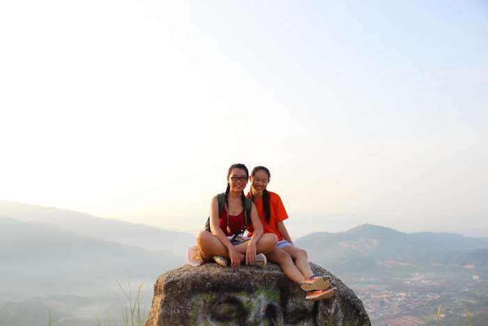 Two girls sitting on a rock on a hilltop