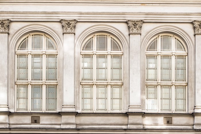 Three arched windows on a white building facade