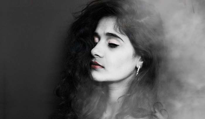Woman with dark hair and smoke