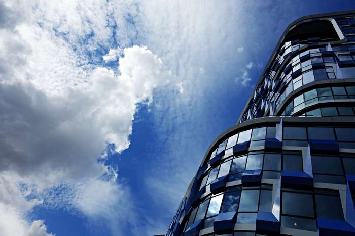 Modern blue glass building against a cloudy sky