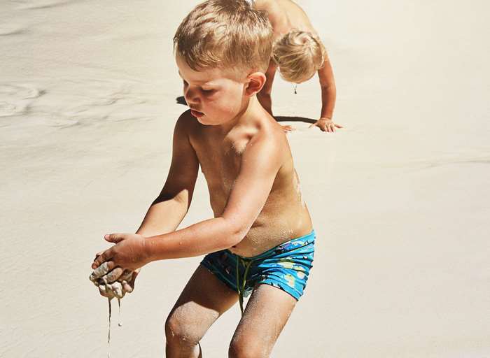 Two young boys playing with sand on a sunny beach