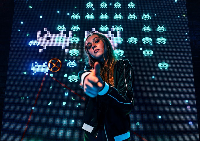 Young girl with finger gun in front of arcade screen