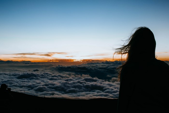 Silhouette of a woman above clouds at sunset in Hawaii