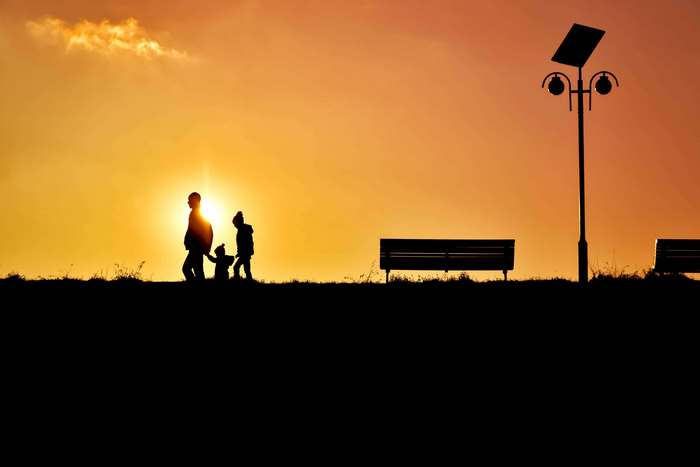 Family silhouette at sunset with street lamp and benches